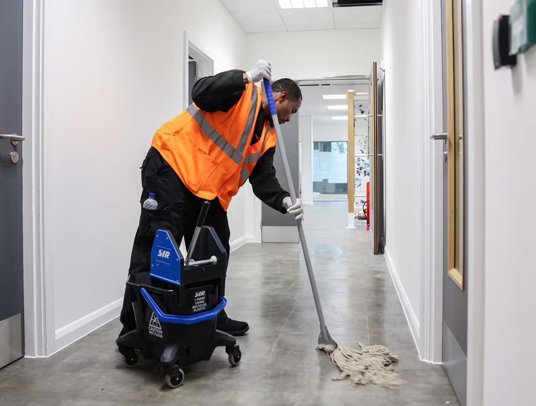 AOG cleaning operative in a modern commercial office corridor